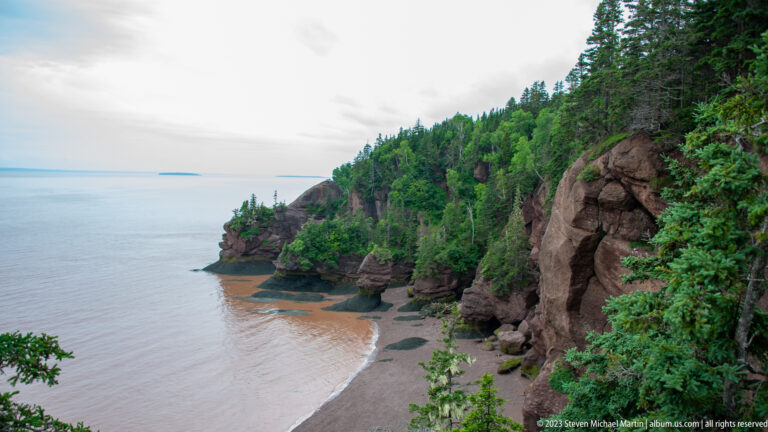 High view along Hopewell Rocks cliffs and sea stacks above exposed orange-brown tidal flats.
