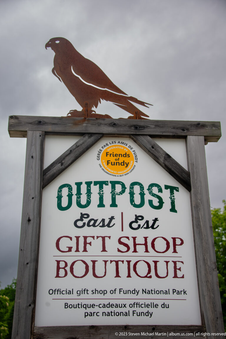 Rustic Outpost East Gift Shop Boutique sign topped by a carved bird silhouette at Fundy National Park.