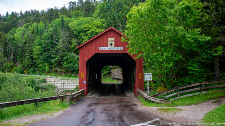 Front entrance of the red Point Wolfe covered bridge with name sign and 23-tonne limit marker.