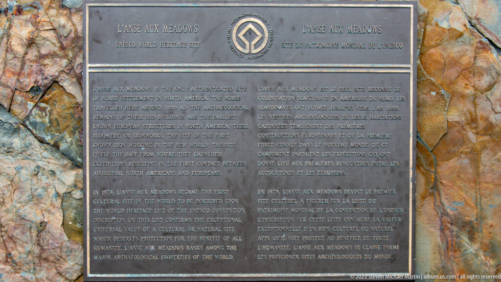 Bronze bilingual World Heritage plaque for L’Anse aux Meadows mounted on a multicolored stone surface.