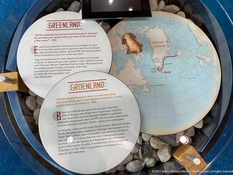Circular map centered on Greenland beside bilingual interpretive text about Norse settlement and westward voyages.