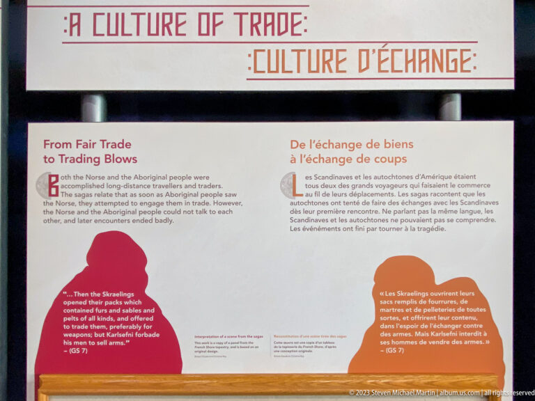 Bilingual museum panel titled From Fair Trade to Trading Blows with red and orange human silhouettes and parallel English and French text.