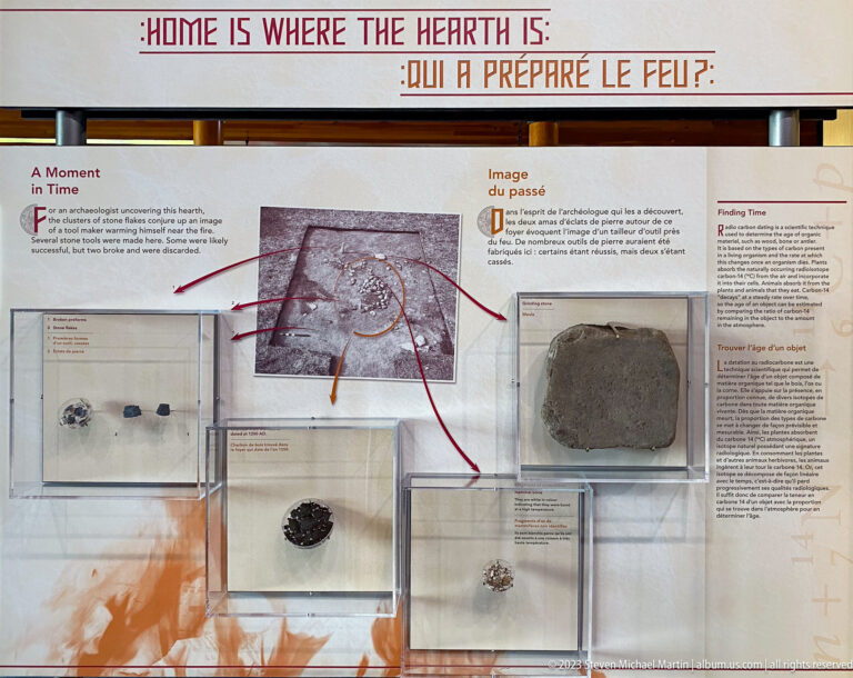 Bilingual A Moment in Time exhibit with excavation photograph, several artifact cases, and red lines connecting finds to archaeological context.