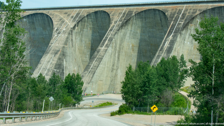 Curving road approaching the towering multiple concrete arches of Daniel-Johnson Dam at Manic-5.