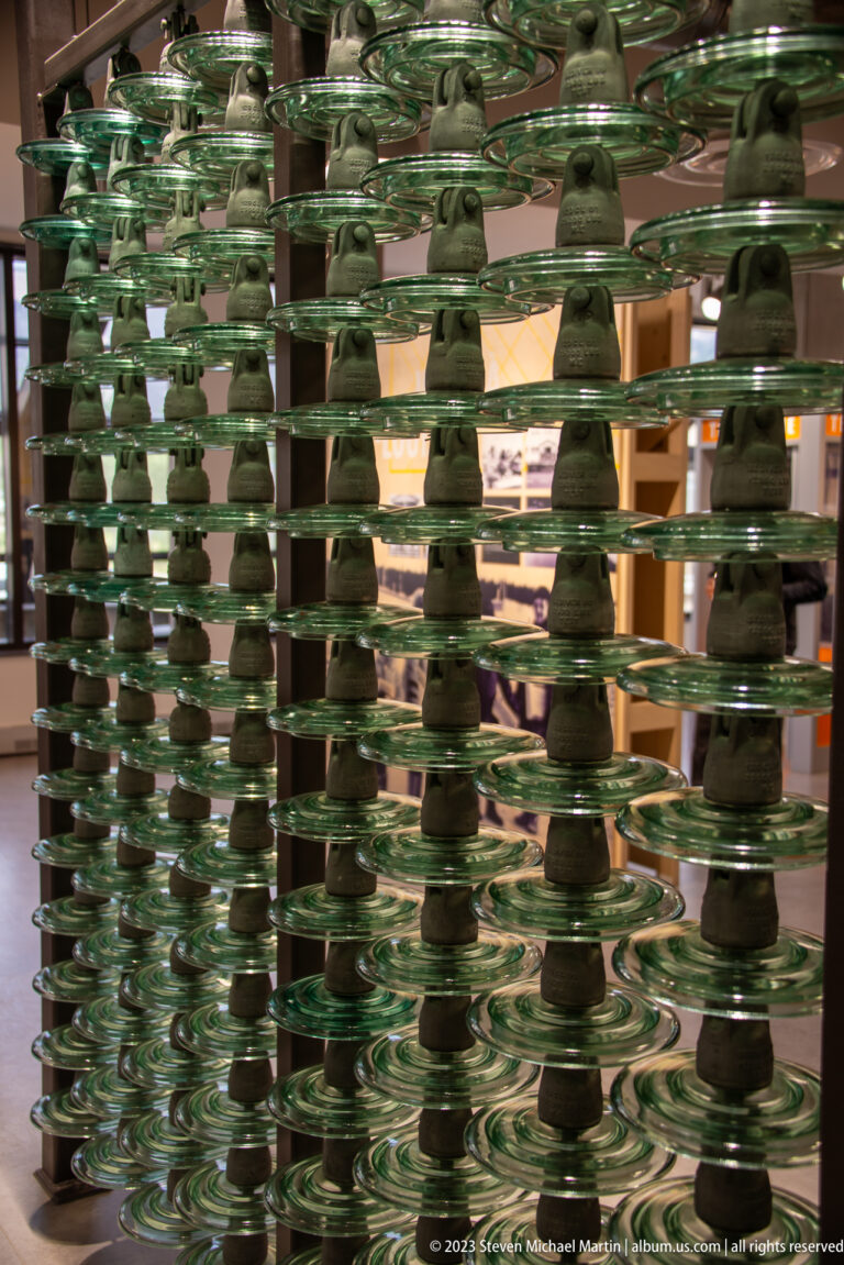 Closely packed rows of green glass electrical insulators stacked in repeating vertical columns indoors.