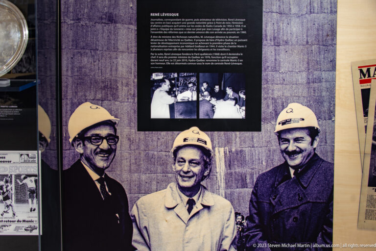Interpretive exhibit with René Lévesque pictured between two men wearing white hard hats.