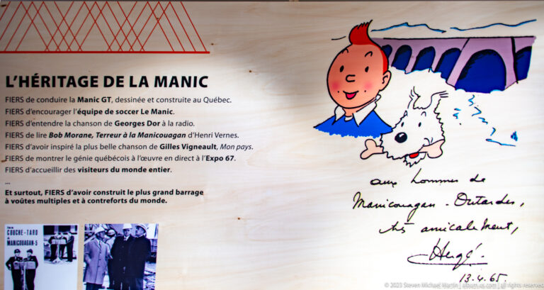 French panel titled “L’Héritage de la Manic” with a signed drawing of Tintin, Snowy, and a concrete dam.