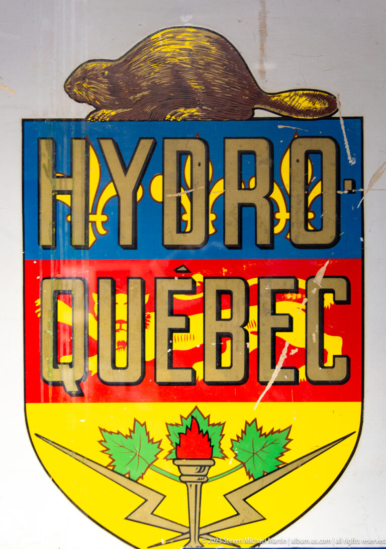 Vintage multicolored HYDRO QUEBEC sign with stylized water, torch, and maple-leaf motifs.