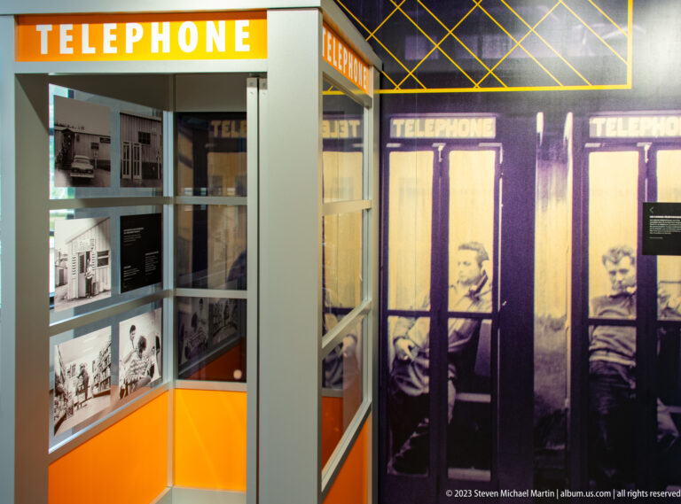 Two reconstructed telephone booths marked “TÉLÉPHONE” beside archival photographs in the Manic-5 exhibit.