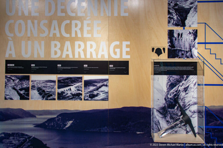 French timeline exhibit titled “Une décennie consacrée à un barrage” with construction photographs and reservoir landscape.