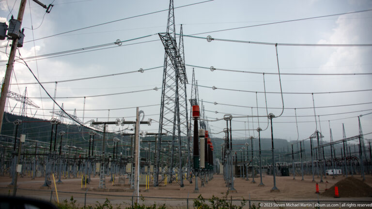 Close view of a high-voltage switchyard with lattice towers, bus lines, insulators, and switching equipment.