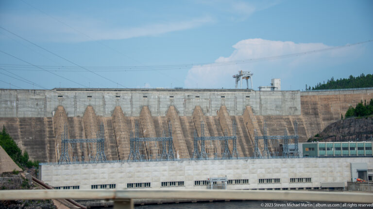 Large Manic-5 hydroelectric complex with repeated concrete buttresses above electrical equipment and a long powerhouse building.