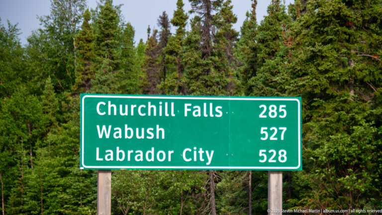 Green highway sign listing Churchill Falls 285 km, Wabush 527 km, and Labrador City 528 km.