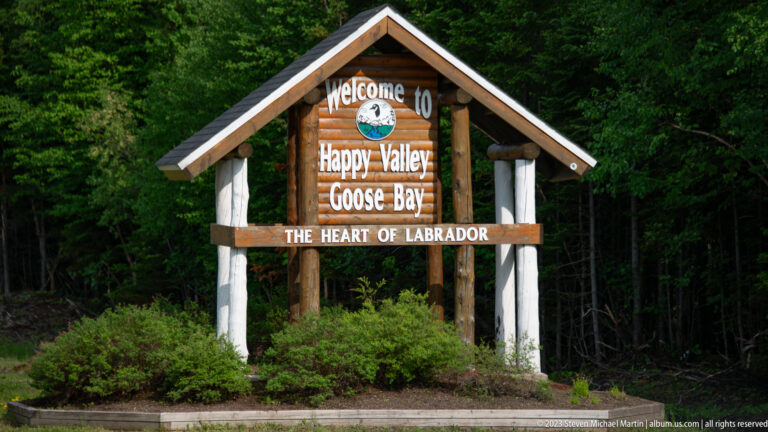 Close view of the rustic Happy Valley-Goose Bay welcome sign with “The Heart of Labrador” on its lower beam.