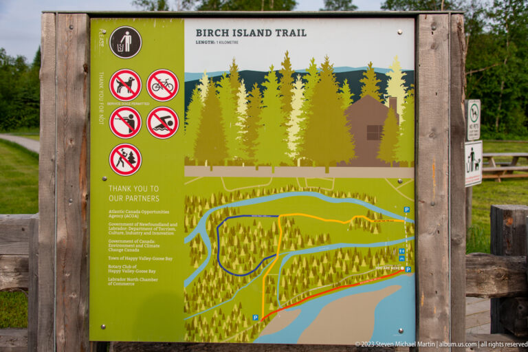 Birch Island Trail information board with route map, forest graphics, and visitor prohibition symbols.