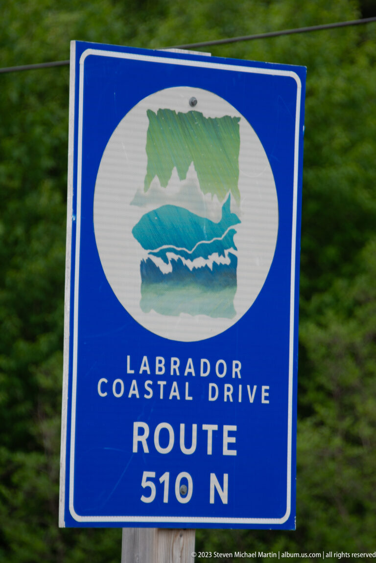 Blue sign reading 'LABRADOR COASTAL DRIVE — ROUTE 510 N' with a stylized coastal emblem.