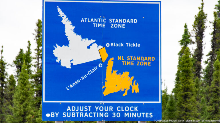 Blue time-zone sign mapping Atlantic and Newfoundland Standard Time and instructing drivers to subtract 30 minutes.
