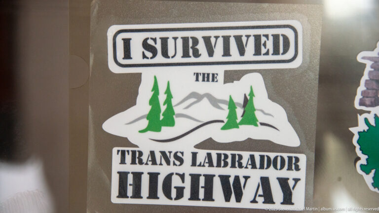 Sticker reading 'I Survived the Trans Labrador Highway' with mountains and evergreen trees.