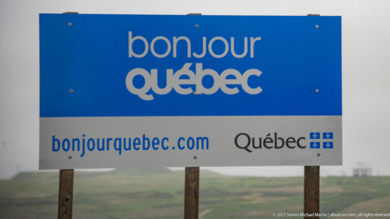 Blue-and-white roadside sign reading 'bonjour Québec' with Québec government branding.