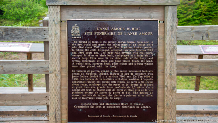 Bilingual bronze plaque headed 'L’Anse Amour Burial Site / Site funéraire de L’Anse Amour' mounted on wood.