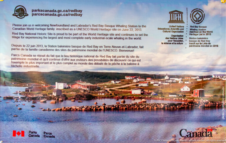 UNESCO and Parks Canada sign for Red Bay Basque Whaling Station above a panoramic photograph of Red Bay harbor.