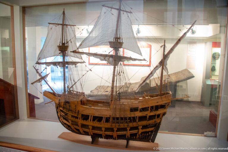Large cutaway wooden sailing-ship model with masts, rigging, exposed decks, ribs, and open hull framing.