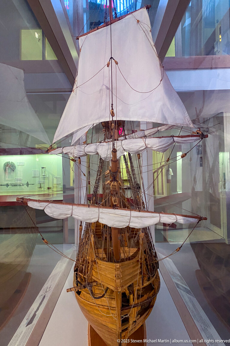 Large cutaway wooden sailing-ship model with cream sails, masts, rigging, and exposed internal decks.