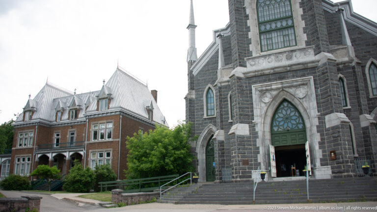 Oblique view of Sacré-Cœur church entrance beside a large red-brick institutional building.