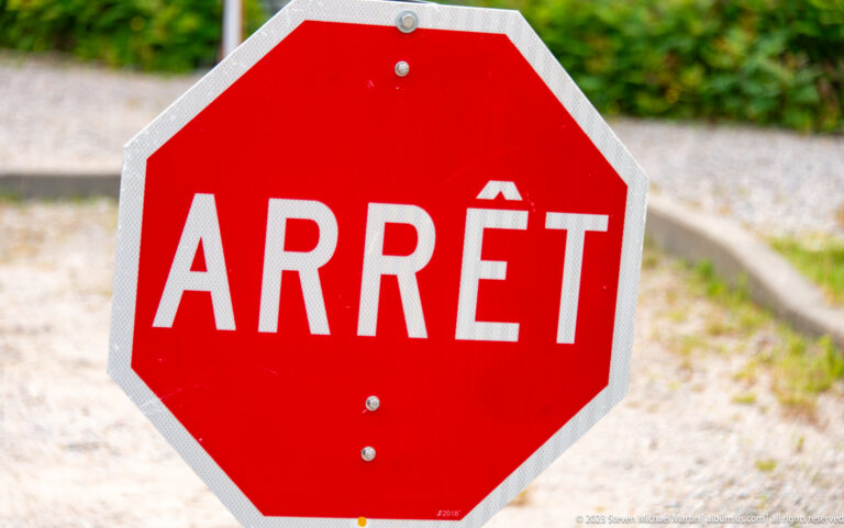 Close-up of a red octagonal Québec stop sign with the white French word “ARRÊT.”