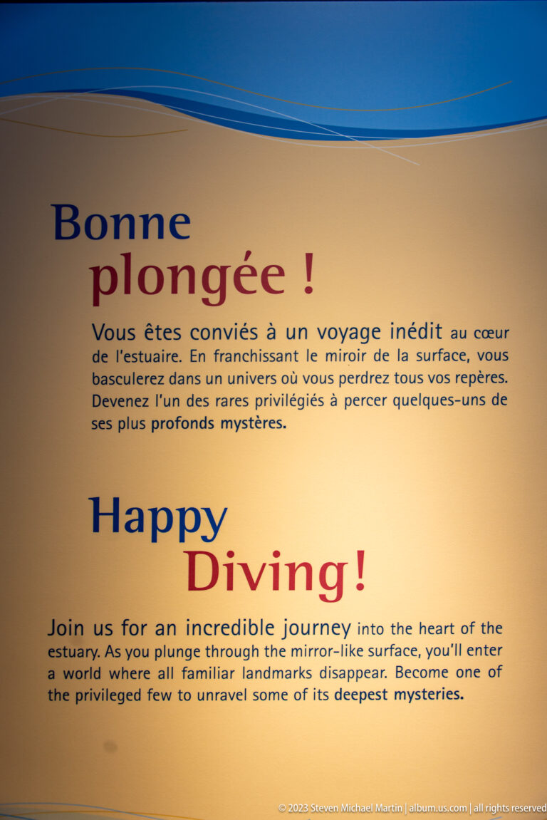 Cream bilingual exhibit panel headed “Bonne plongée! / Happy Diving!” in large blue and red lettering.