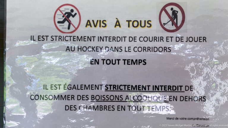 French notice headed “AVIS À TOUS” with prohibition symbols and rules about corridor behavior and alcohol.