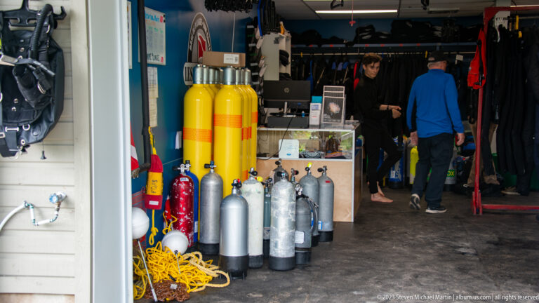 Yellow and gray scuba cylinders, ropes, and diving gear stored inside a marine service room.