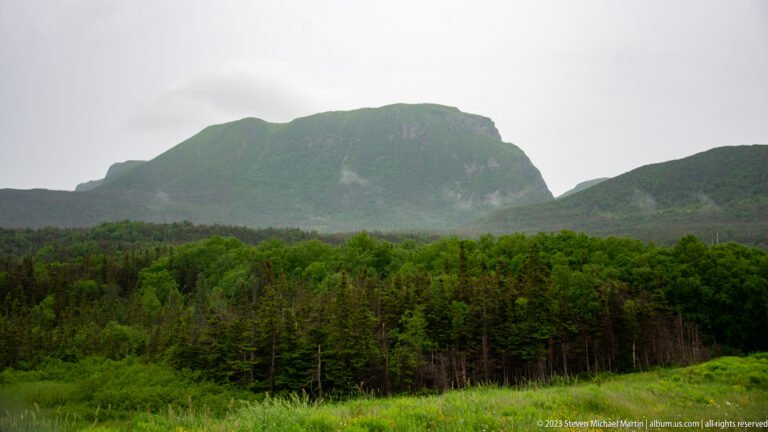 Large flat-topped mountain rising above dense forest beneath an overcast sky.