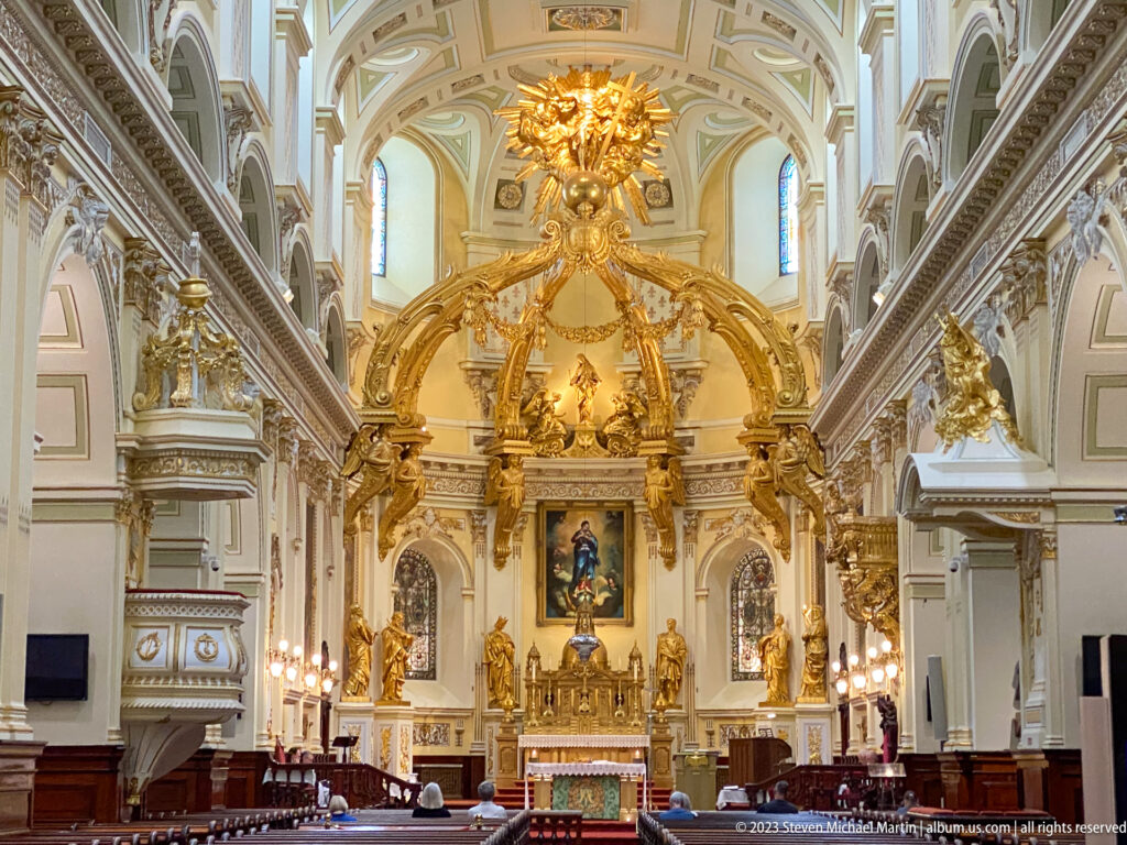 Close view of Notre-Dame de Québec's gilded sanctuary with sweeping ornamental arches, statues, garlands, and central altar.