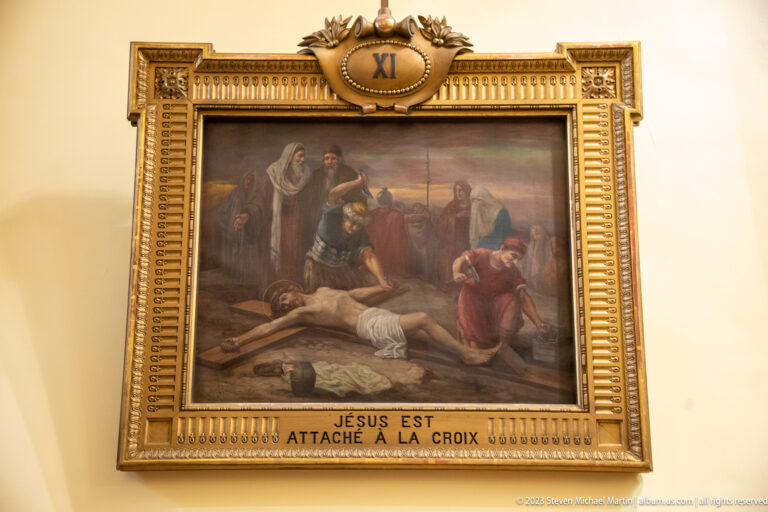 Framed Station XI painting showing Jesus being fastened to the cross, with French title below and XI above.