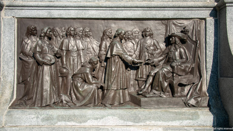 Bronze relief with a central cleric greeting a seated man as groups of robed and formally dressed figures look on.