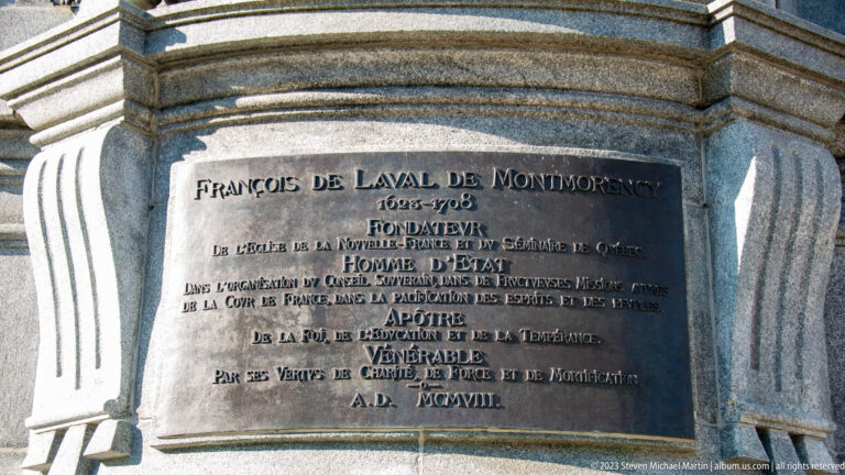 Bronze French inscription plaque for François de Laval de Montmorency mounted on a carved stone monument.