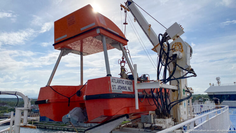 Orange Atlantic Vision rescue craft rests beneath a large davit and launching mechanism on the ferry's open deck.