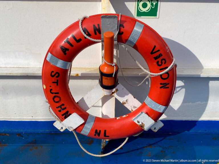 Orange lifebuoy labeled Atlantic Vision, St. John's, and NL mounted against the ferry's white-and-blue rail.