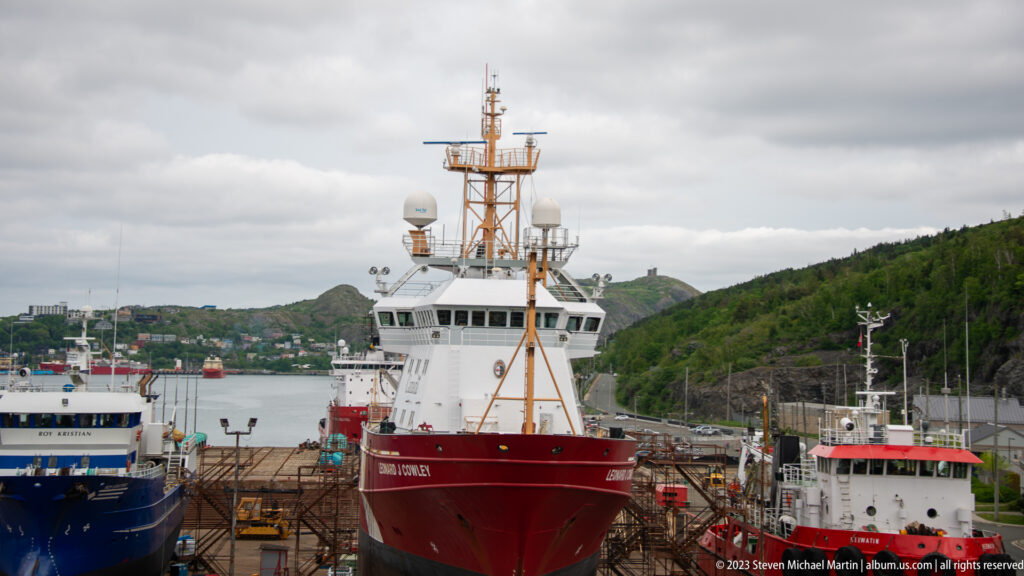 Red-hulled Atlantic Kingfisher docked bow-on among other working vessels in St. John’s harbor.