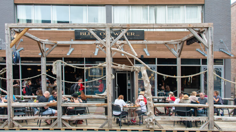 Diners seated at long tables on Blue on Water’s rustic wood-and-rope patio.