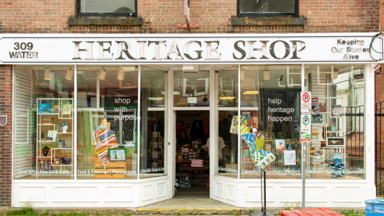 White Heritage Shop storefront at 309 Water Street with open doorway, display windows, books, and colorful merchandise.