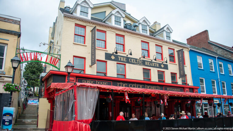 The Celtic Hearth restaurant with red awnings and patio beside the arched William’s Lane entrance.