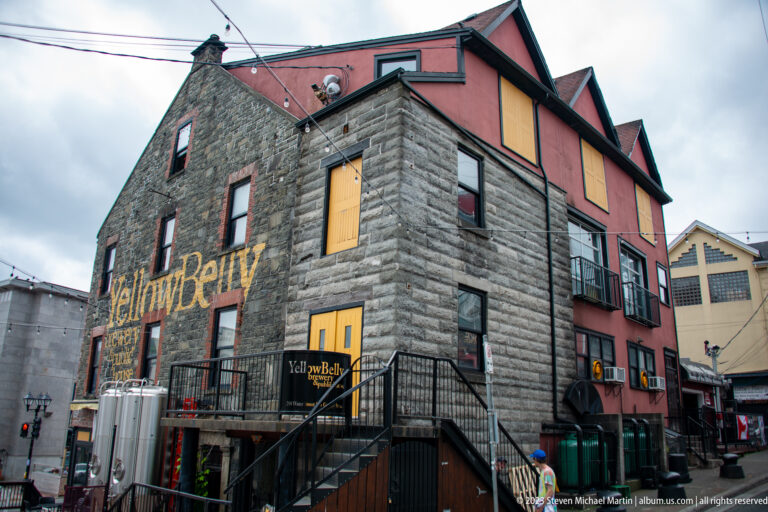 YellowBelly Brewery & Public House in a large stone building with yellow lettering, exterior stairs, and brewing equipment.