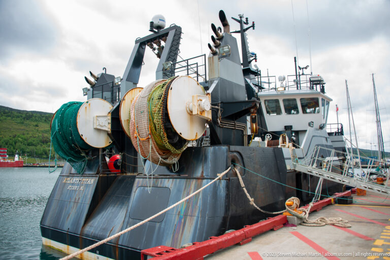 Atlantic Titan moored stern-to with large net drums, fishing gear, gantry, ropes, bridge, and mast.