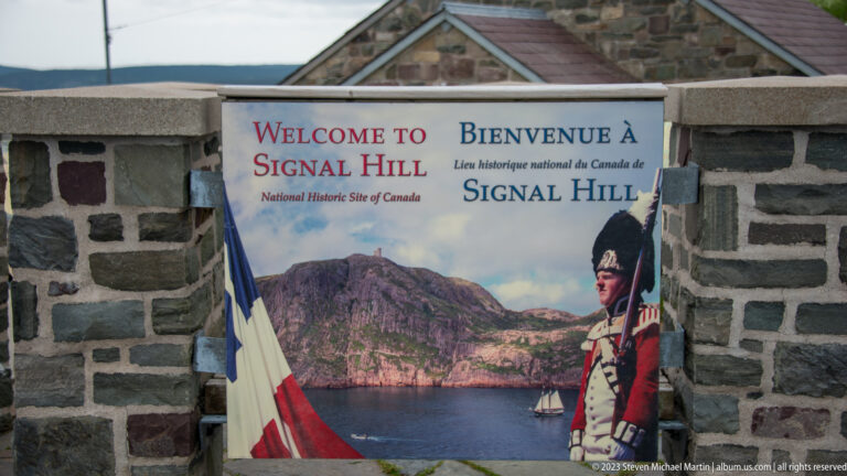 Bilingual Welcome to Signal Hill panel in a stone wall, illustrated with the harbor and a historic soldier.