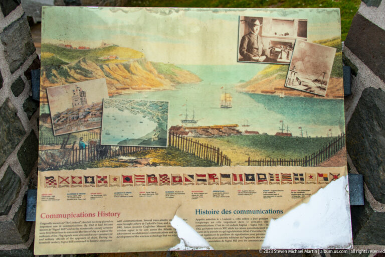 Communications History panel with a harbor painting, archival photographs, and a row of maritime signal flags.