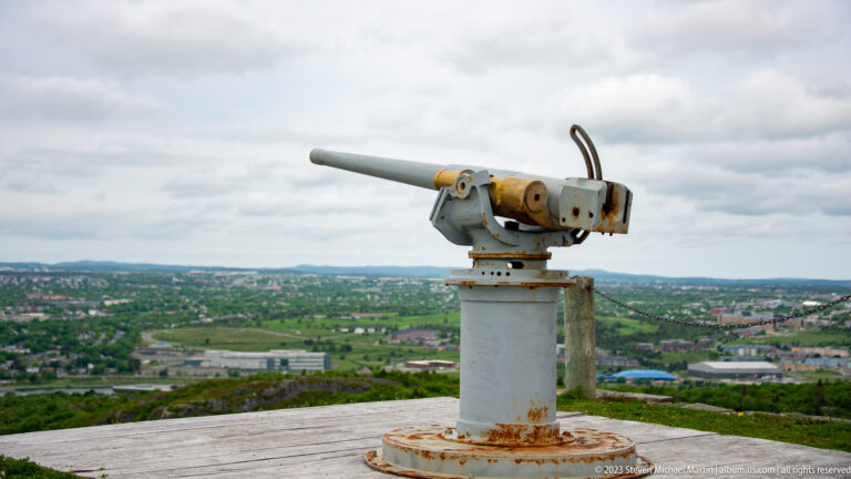 Weathered coastal gun on a rotating pedestal at Signal Hill, with St. John’s landscape in the distance.
