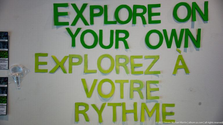 Large green bilingual wall text reads 'Explore on your own' and 'Explorez à votre rythme.'