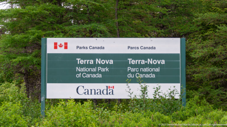 Bilingual Parks Canada sign reading Terra Nova National Park of Canada and Parc national Terra-Nova du Canada in forest.